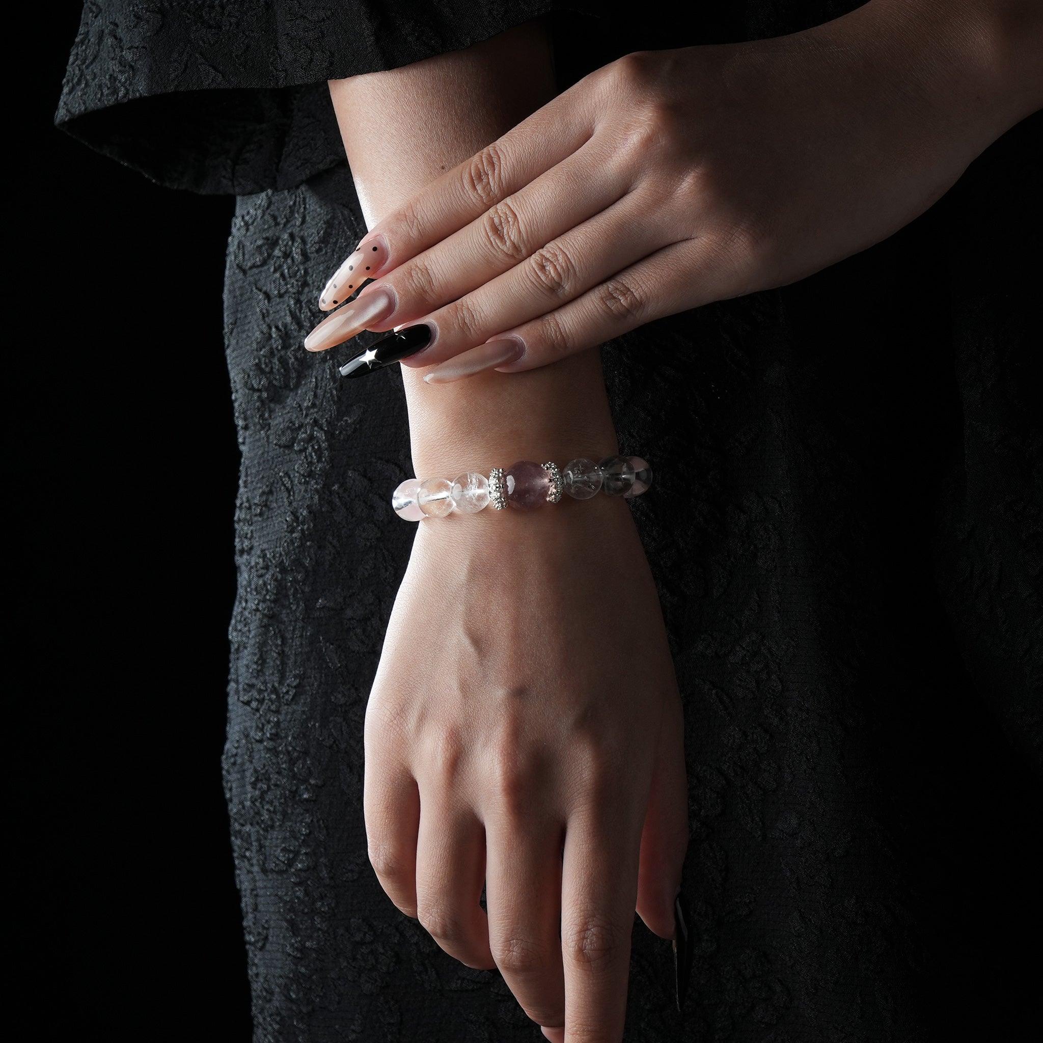 Elegant bracelet featuring alternating clear and rose quartz beads with silver spacer accents, worn on a woman's wrist in a black dress.