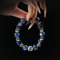 Kyanite, lapis lazuli, and golden rutile quartz beaded bracelet with square lapis stones, held by hand on black background for wisdom and energy flow.