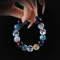 Mixed gemstone and clear quartz beaded bracelet with unique multicolor stones, held by hand on black background for harmony and creative energy.