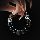 Obsidian, tiger’s eye, and clear quartz bracelet with moon-textured lava stone centerpiece, held by hand on black background for grounding and mystery.