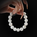 White moonstone beaded bracelet with soft glow, held by hand on black background for emotional balance and feminine energy.